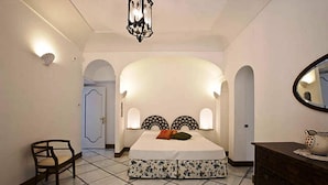A bedroom with a bed, a chair, a dresser, and a mirror. - Villa Le Sirene in Positano (Positano)