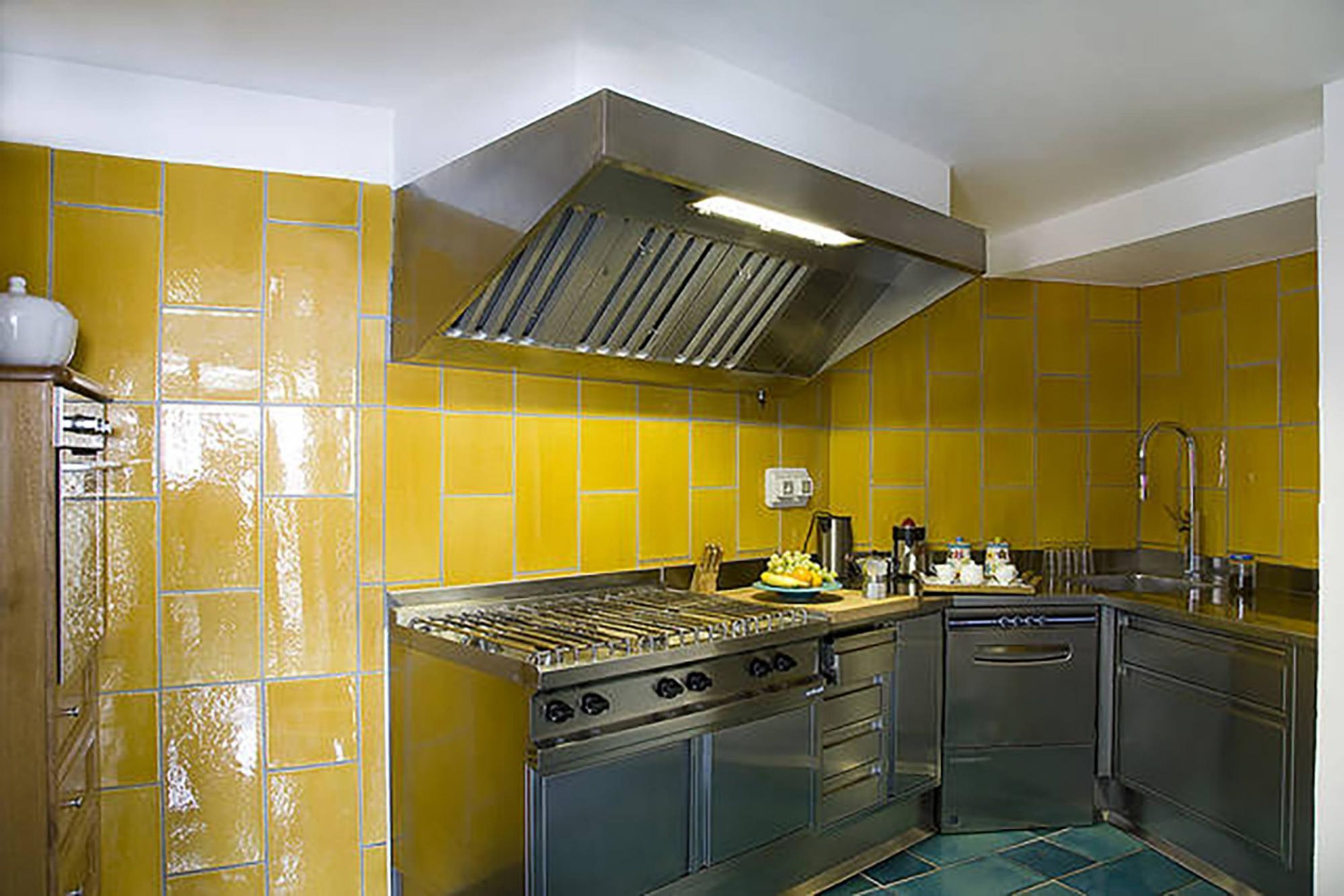 Een keuken met gele tegels, roestvrijstalen apparatuur en een inbouwoven.
