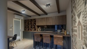 A modern kitchen with a bar area, wooden beams on the ceiling, and a patterned wall.
