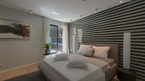 A modern bedroom with a bed, a window with curtains, a wall-mounted artwork, and a ceiling light.
