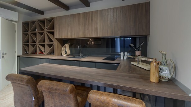A modern kitchen with a wooden countertop, built-in shelves, and a central island with seating.