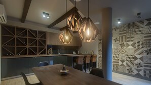 A modern kitchen with a dining area, geometric patterned wall, and pendant lighting.