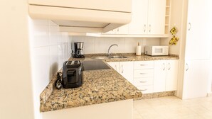 A compact kitchen with white cabinets, a granite countertop, a coffee maker, a toaster, and a microwave. - TIJERITAS COOL SEA BREEZE (Los Cristianos)