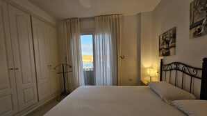 A bedroom with a large bed, a wardrobe, a window with curtains, and a painting on the wall. - TIJERITAS COOL SEA BREEZE (Los Cristianos)