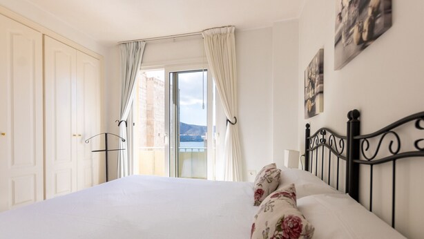 A bedroom with a bed, curtains, a balcony, and a city view. - TIJERITAS COOL SEA BREEZE (Los Cristianos)