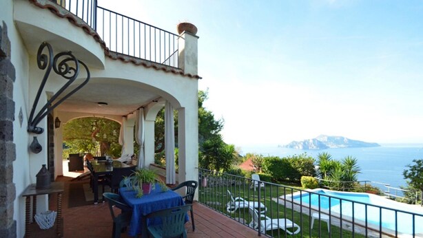 A patio with a table and chairs, a pool, and a view of the sea. - Villa Posidonia in Massa Lubrense (Massa Lubrense)
