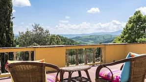 A balcony with wicker furniture and a view of rolling hills. - Villa Il Giardino in Radicofani (Radicofani)