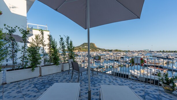 A terrace with a view of a marina, outdoor seating, and potted plants. - Baia Flegrea Meublè (Bacoli)
