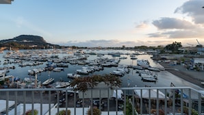 A marina with numerous boats docked, a hill in the background, and a restaurant with outdoor seating. - Baia Flegrea Meublè (Bacoli)