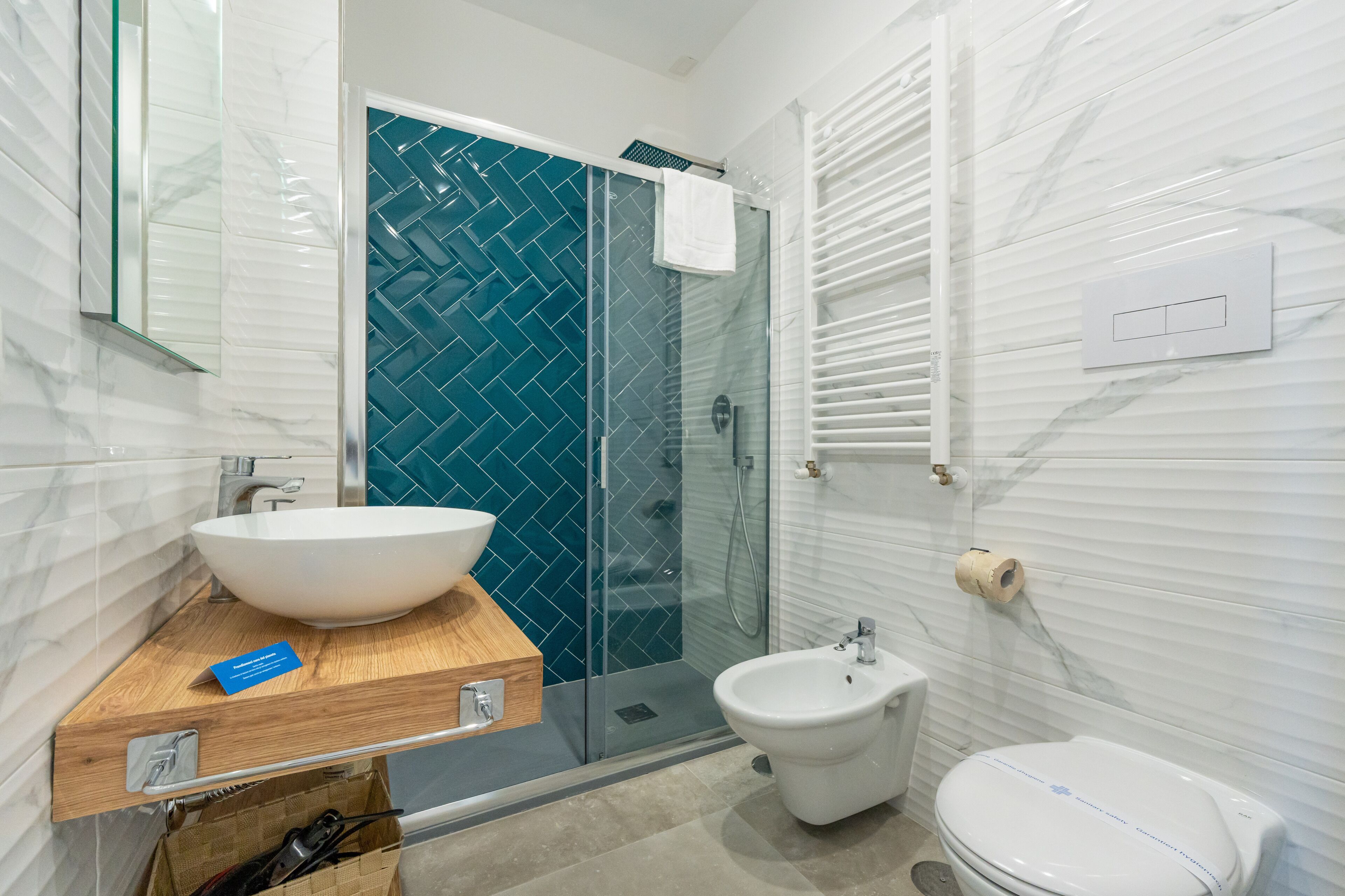A bathroom with a white sink, a bidet, a toilet, and a glass shower enclosure.