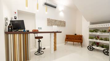 Un intérieur moderne avec un comptoir de bar en bois, un canapé orange à motifs capitonnés et une étagère blanche agrémentée de plantes.