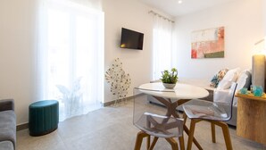 A modern living room with a glass table, clear chairs, a sofa, a TV, and a painting on the wall. - Baia Flegrea Meublè (Bacoli)