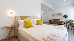 A modern hotel room with a large bed, a bedside table, a sofa, and a dining area. - Baia Flegrea Meublè (Bacoli)