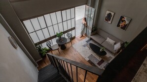 Ein modernes Interieur mit Treppe, Balkon, einer Couch und einem Essbereich.