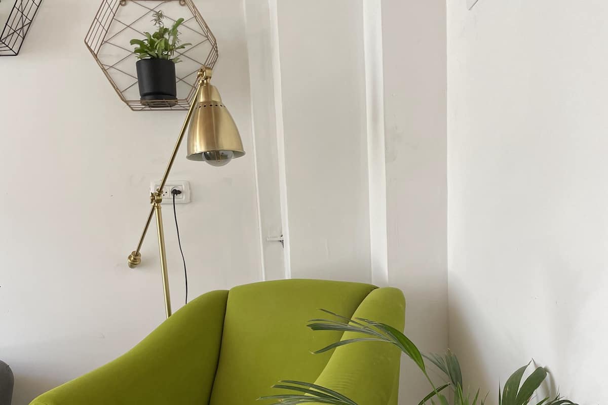 A green armchair with a potted plant beside it.
