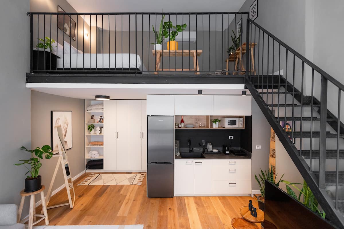 A compact, modern apartment with a kitchenette, a dining area, and a small balcony.
