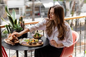 Iemand zit aan een buitentafel met verschillende soorten eten en planten.