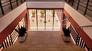 A staircase with a metal railing, potted plants, and a view of an outdoor area with a gate and plants.
