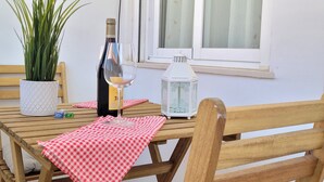A wooden table with a checkered tablecloth, a bottle of wine, a wine glass, a potted plant, and a lantern.