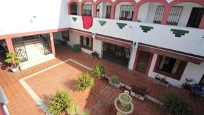 A courtyard with tiled flooring, potted plants, and a fountain.