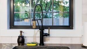 A kitchen sink with a modern faucet, a soap dispenser, and a dish soap bottle.