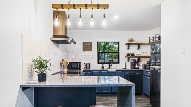 A modern kitchen with a central island, built-in appliances, and a welcoming sign.