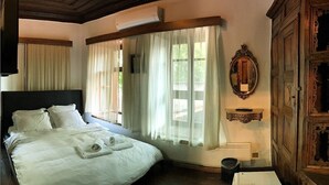 A bedroom with a large bed, a wooden headboard, a window with sheer curtains, a mirror, and a wooden cabinet. - Anfora Otel & Sarap Evi (Edremit)