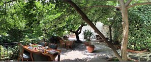 An outdoor dining area with a wooden table and chairs, surrounded by lush greenery and potted plants. - Anfora Otel & Sarap Evi (Edremit)