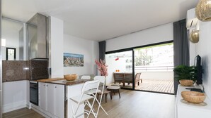 Een moderne keuken met granieten aanrechtbladen, witte kastjes en een eethoek met een houten tafel en stoelen.