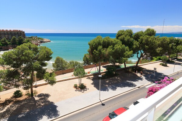 A coastal view with a beach, trees, and a road. - AirCon Apartment · Beachfront · WiFi · UHC SCALA MAR 305 (Salou)