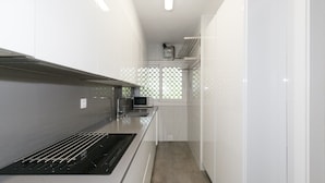 A modern kitchen with white cabinetry, a stainless steel range hood, and a microwave. - AirCon Apartment · Beachfront · WiFi · UHC SCALA MAR 305 (Salou)