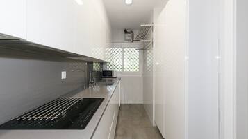 Una cocina moderna con armarios blancos, una campana extractora de acero inoxidable y un microondas.