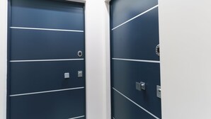 Deux portes bleu foncé, ornées de lignes horizontales et d’un logo circulaire, chacune dotée d’un trou de serrure et d’une serrure.