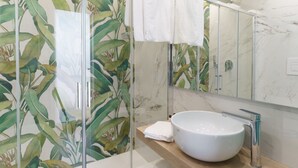 Une salle de bain avec un grand lavabo blanc, un miroir et une cabine de douche dotée d’une porte en verre.