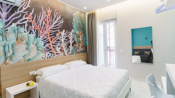 Une chambre d’hôtel avec un lit, une table de chevet, un bureau et une chaise.