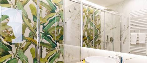 A modern bathroom with a large mirror, a white sink, and a glass shower enclosure.