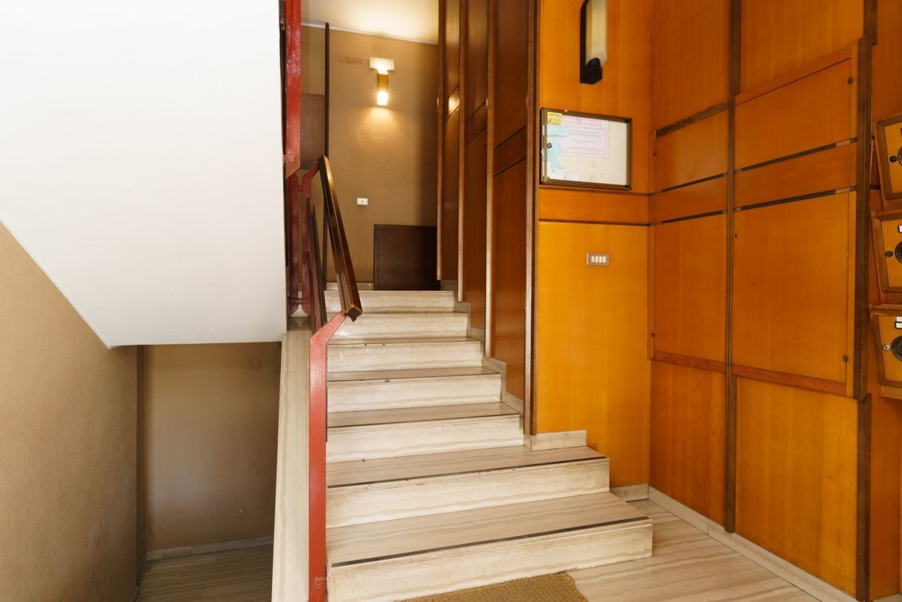 Eine Treppe mit Holzverkleidung und Handlauf, die zu einer Zwischenebene mit einem Schild führt.