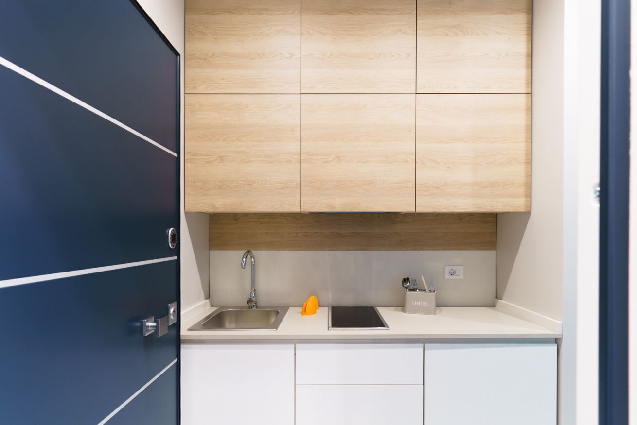 Eine moderne Küche mit Spüle aus Edelstahl, Holzschränken und einer weißen Arbeitsplatte.