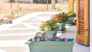 Un bâtiment en bois doté d’un porche, de sièges en plein air et de plantes en pot.