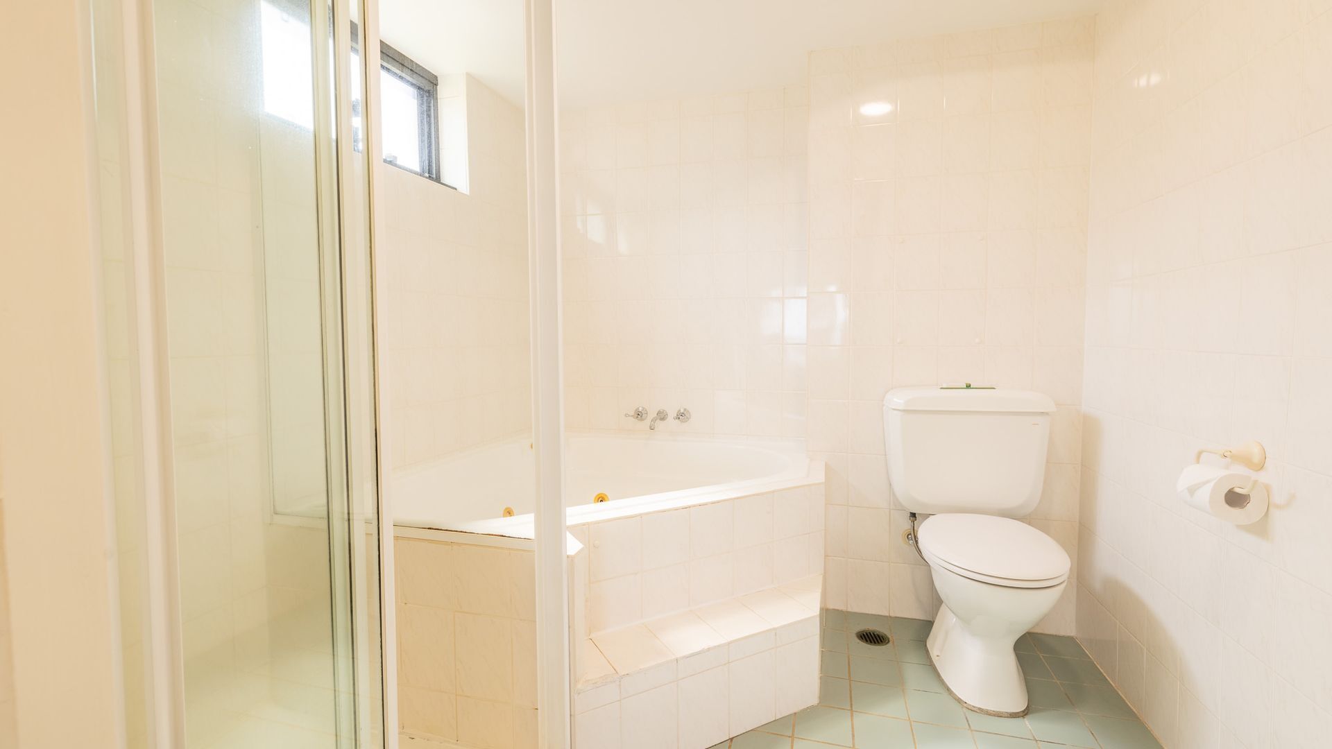 A bathroom with a toilet, a bathtub, and a glass shower enclosure.