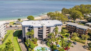 Un hotel de varios pisos con piscina, rodeado de exuberante vegetación y una playa.