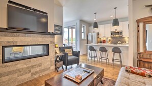A modern living room with a fireplace, a flat-screen TV mounted above it, and a cozy seating area with a sofa and a coffee table. - Grand Lake Condo w/ Balcony & Mountain Views (Grand Lake)