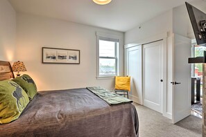 A bedroom with a bed, a window, a door, and a chair. - Grand Lake Condo w/ Balcony & Mountain Views (Grand Lake)