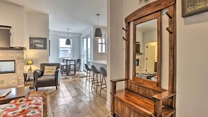 A modern living room with a fireplace, a large mirror, and a dining area with bar stools. - Grand Lake Condo w/ Balcony & Mountain Views (Grand Lake)
