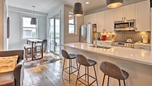 A modern kitchen with a central island, stainless steel appliances, and bar stools. - Grand Lake Condo w/ Balcony & Mountain Views (Grand Lake)
