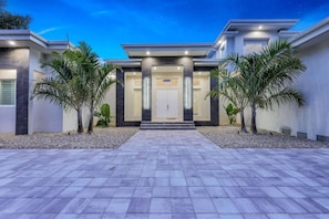 A modern house with a symmetrical facade, a central entrance, and a paved driveway.