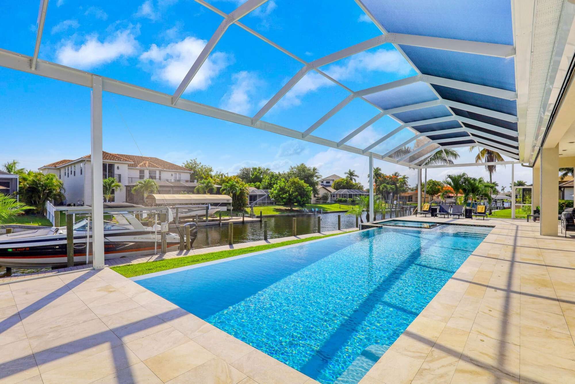A swimming pool with a clear blue water, surrounded by a covered area with a roof structure.
