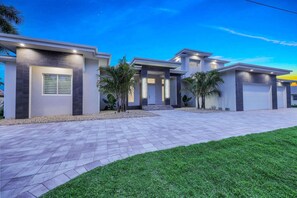 A modern two-story house with a driveway, garage, and a well-maintained lawn. - Villa Juhara - Welcome to Paradies (Cape Coral)