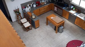 A modern kitchen with a dining area, a living room with a sofa and a coffee table, and a staircase leading to another level. - Gîtes les 2 Clos au Pied du Mont (Pontorson)