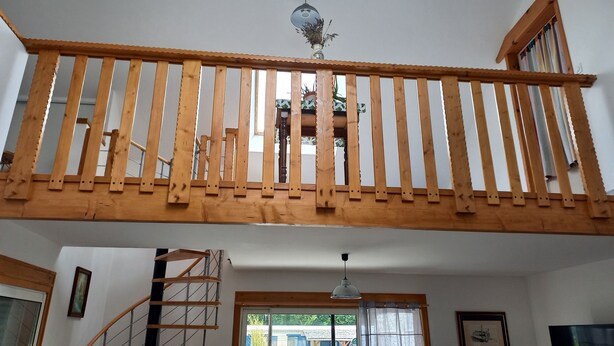 A wooden balcony with a railing, a spiral staircase, and a ceiling fan. - Gîtes les 2 Clos au Pied du Mont (Pontorson)
